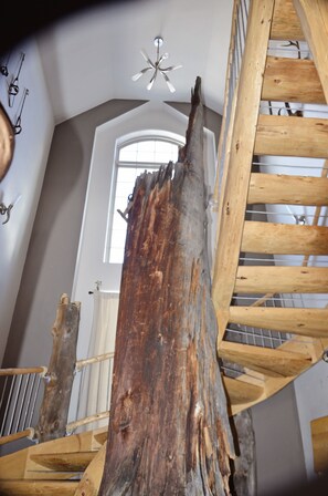 A spiral staircase with a rustic wooden design, a large window with a view of the sky, and a ceiling fan. - Custom log cabin nestled in Powderhorn Ski Resort. Great in winter or summer. (Mesa)