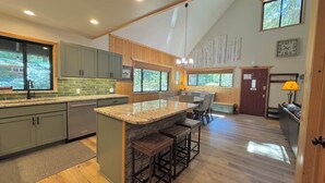 A modern kitchen with a central island, wooden cabinets, and large windows.