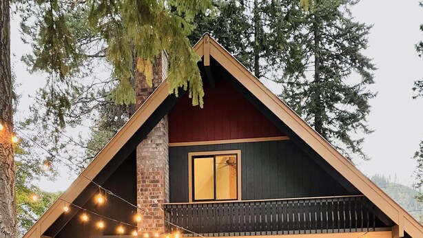 A lodge with a stone facade, a red door, and outdoor seating.