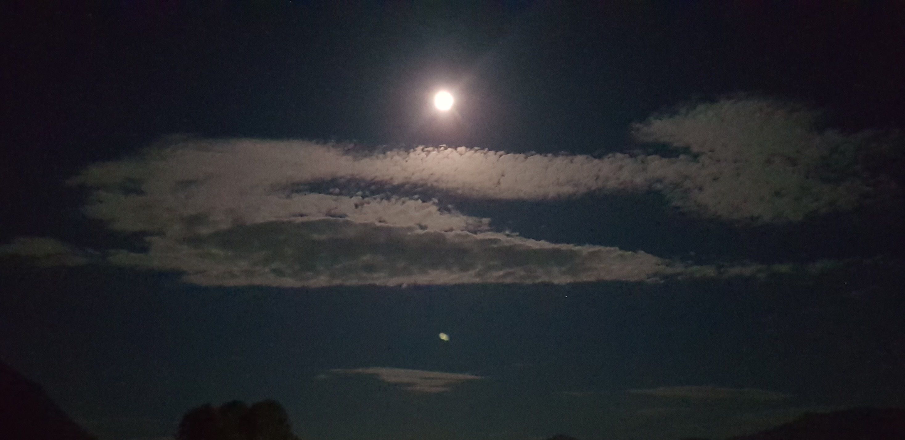 A night sky with a bright moon and a smaller moon or planet visible in the distance.