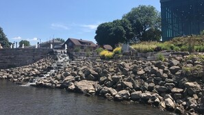 A riverside view with a stone staircase leading down to the water, a modern building, and a traditional house in the background.