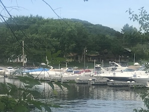 Un puerto deportivo con barcos amarrados, rodeado de vegetación y casas al fondo.