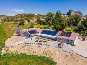 A two-story house with a large patio area, solar panels on the roof, and a fenced yard.