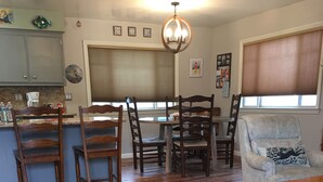 A dining area with wooden chairs and a table, a kitchen with a coffee maker, and a patterned rug on the floor. - Harbor House in Morro Bay  (Morro Bay)