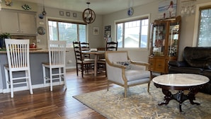 A spacious living area with a wooden floor, a dining table with chairs, a sofa, and a coffee table. - Harbor House in Morro Bay  (Morro Bay)