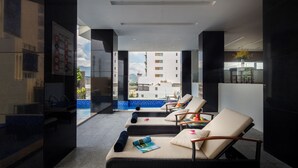 A modern hotel room with a balcony, lounge chairs, and a view of the cityscape. - Red Sun Nha Trang Hotel (Nha Trang)