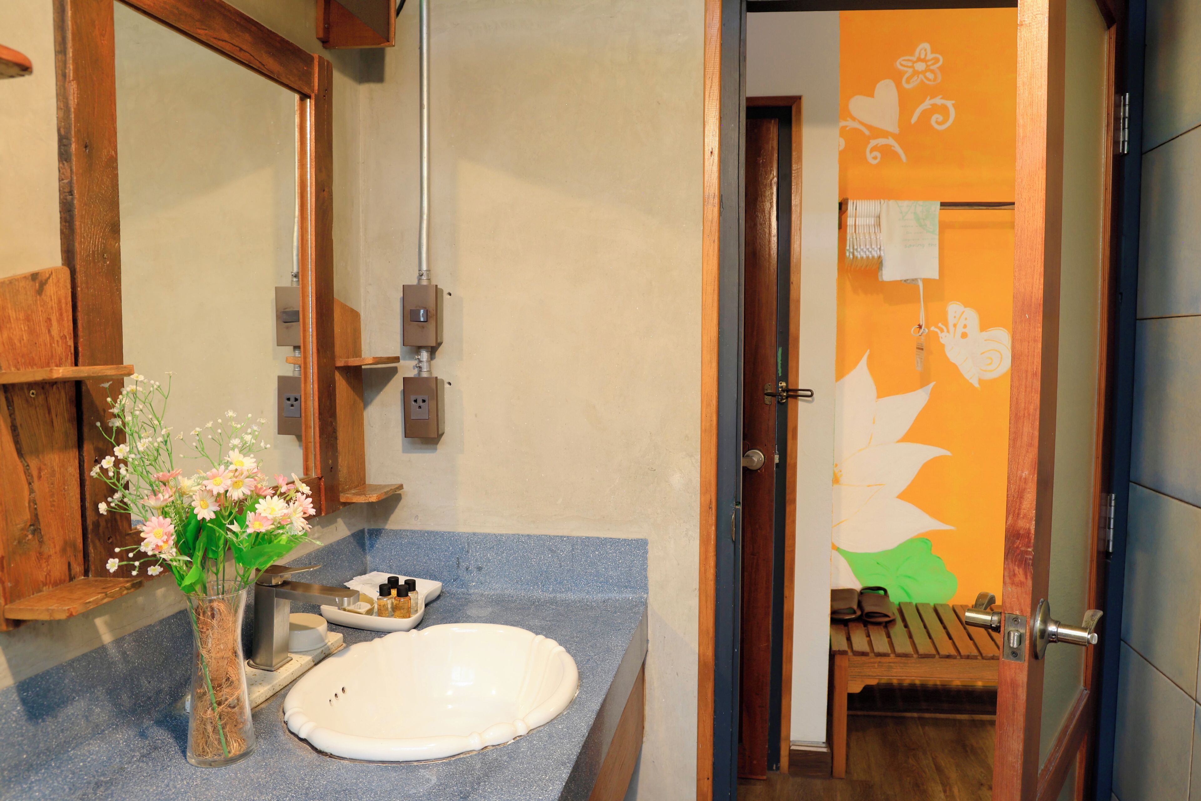 A bathroom with a sink, mirror, and a wooden bench.