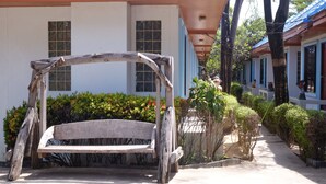 A wooden bench in a courtyard with a white building in the background. - Chayta Resort (Rayong)