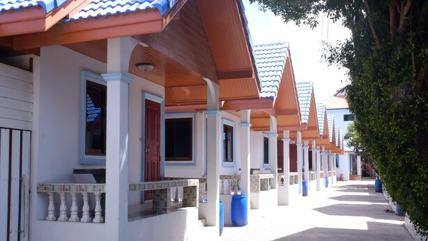 A row of white buildings with blue-tiled roofs and wooden balconies. - Chayta Resort (Rayong)