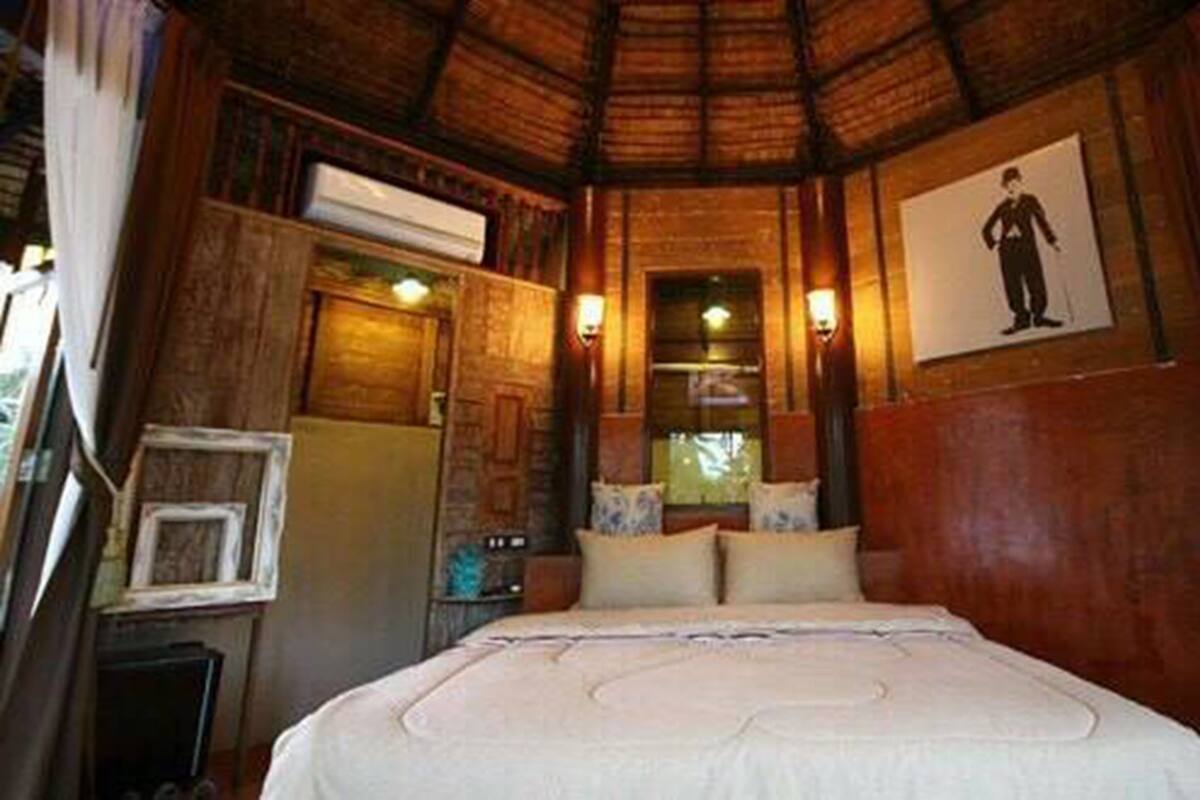 A wooden room with a bed, a window, and a picture on the wall.