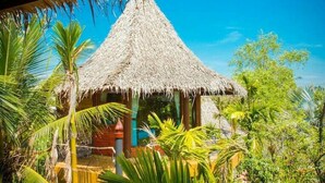 A thatched-roof hut surrounded by lush tropical vegetation. - Amphawa Club (Amphawa)