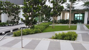 Un'area esterna curata con aiuole, un vialetto lastricato, alberi e un elemento decorativo a base d'acqua.