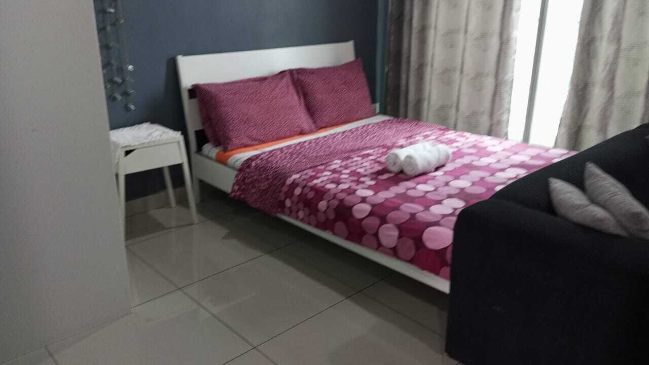 Un dormitorio con cama, mesita de noche, silla y ventana con cortinas.