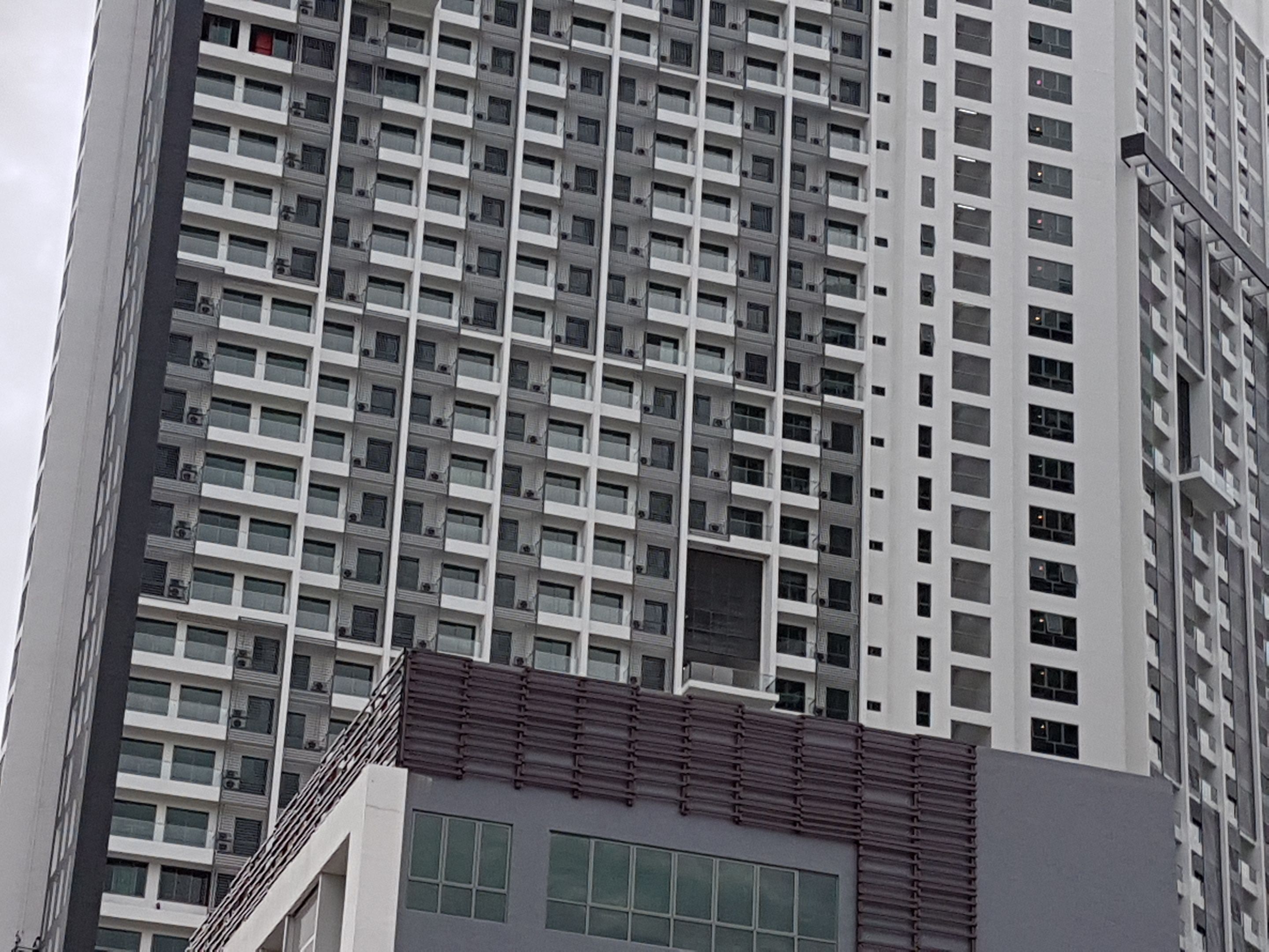 Een hoog gebouw met een raster van ramen en balkons.