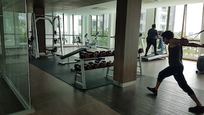 Una palestra con attrezzature per esercizi, ampie finestre e una persona che si allena.