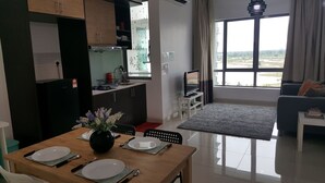 A modern apartment with a dining area, kitchen, living room, and a large window offering a view of the outdoors. - Cyberjaya Vega Residensi (Cyberjaya)