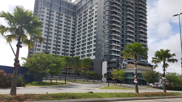 A modern high-rise building with multiple balconies, surrounded by palm trees and greenery. - Cyberjaya Vega Residensi (Cyberjaya)