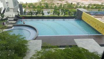 A large swimming pool with a circular section, surrounded by a deck and greenery.