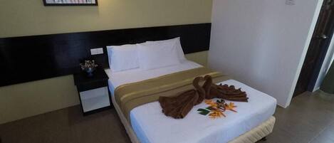 Una habitación de hotel con cama, mesita de noche, lámpara de pared y una puerta.