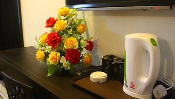 A coffee maker, a remote control, and a floral arrangement on a table.