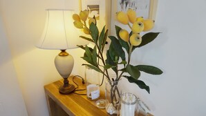 A wooden table with a lamp, a vase with a plant, and a candle holder.