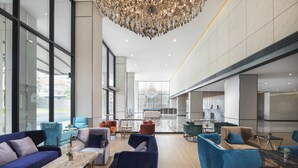 Un hall d’entrée spacieux, doté de meubles modernes, de grandes fenêtres et d’un lustre.