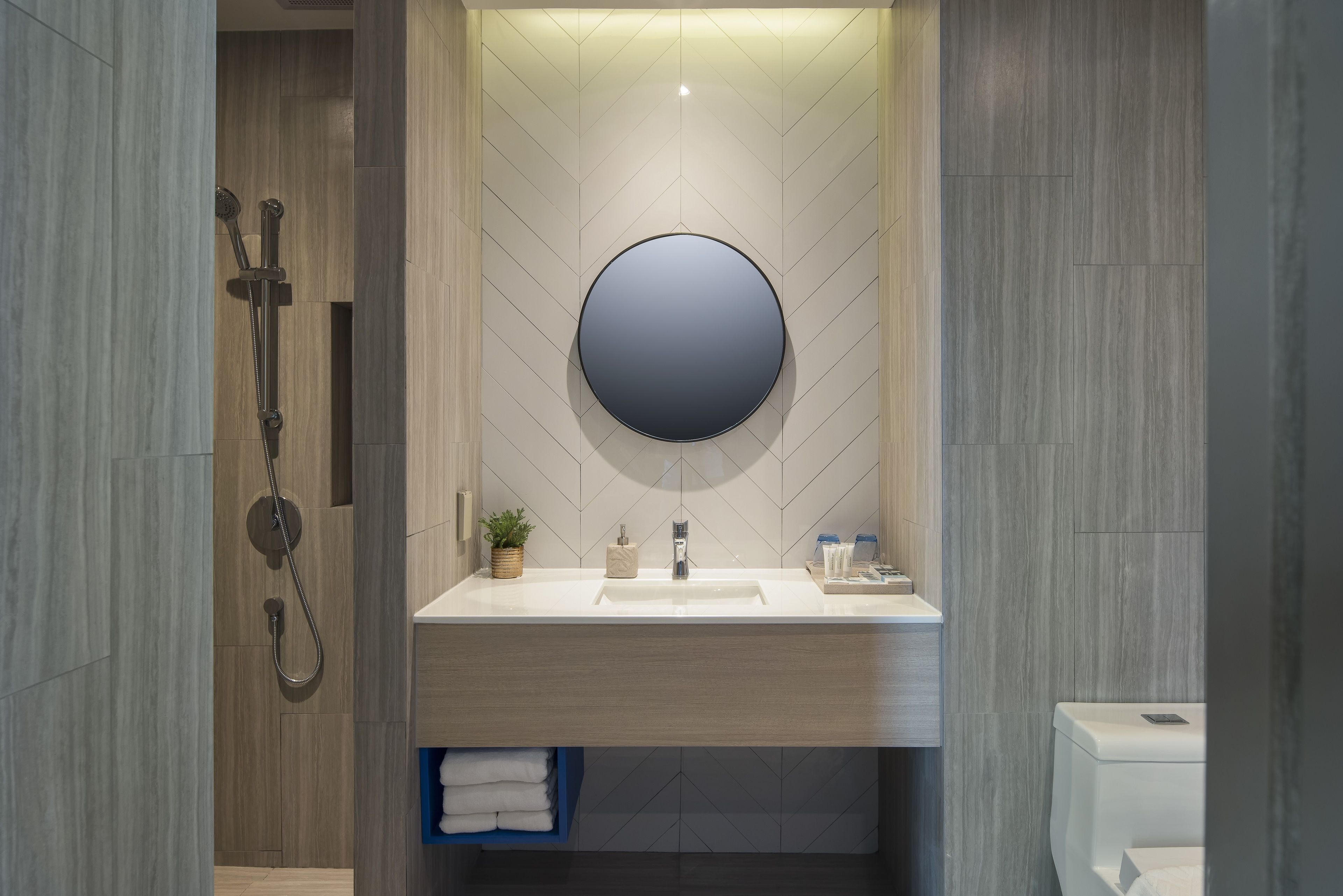 A modern bathroom with a large mirror, a sink, and a shower.
