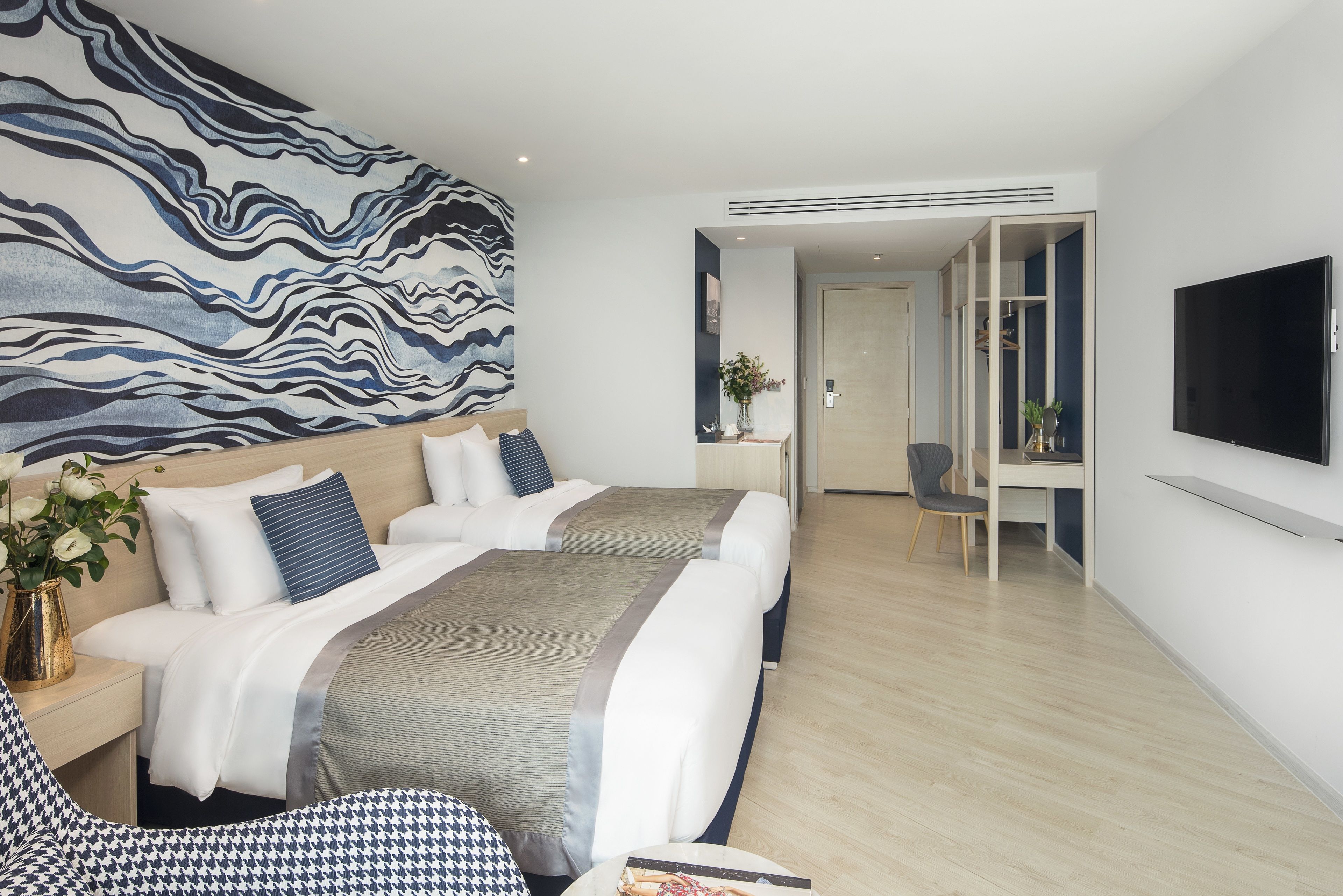 A modern hotel room with a large bed, a desk, and a TV.