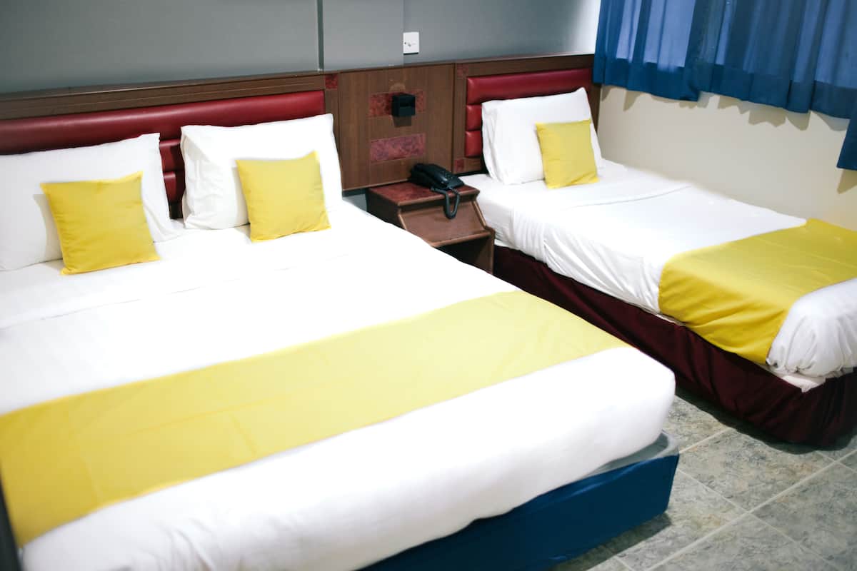 Two single beds with yellow and white bedding, a wooden nightstand with a telephone, and a red headboard.