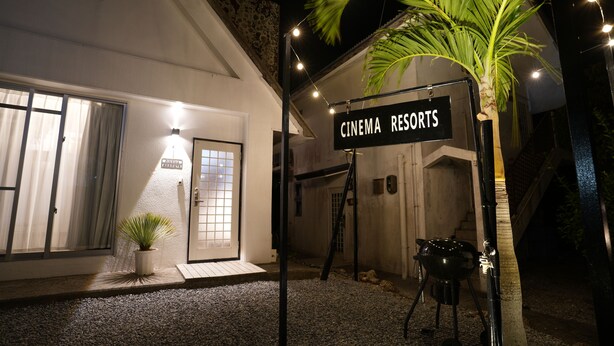 Placa para 'CINEMA RESORTS' com uma palmeira e iluminação externa.