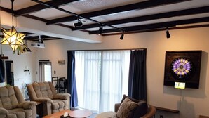 Sala de estar com dardos, projetor e uma janela grande com cortinas.