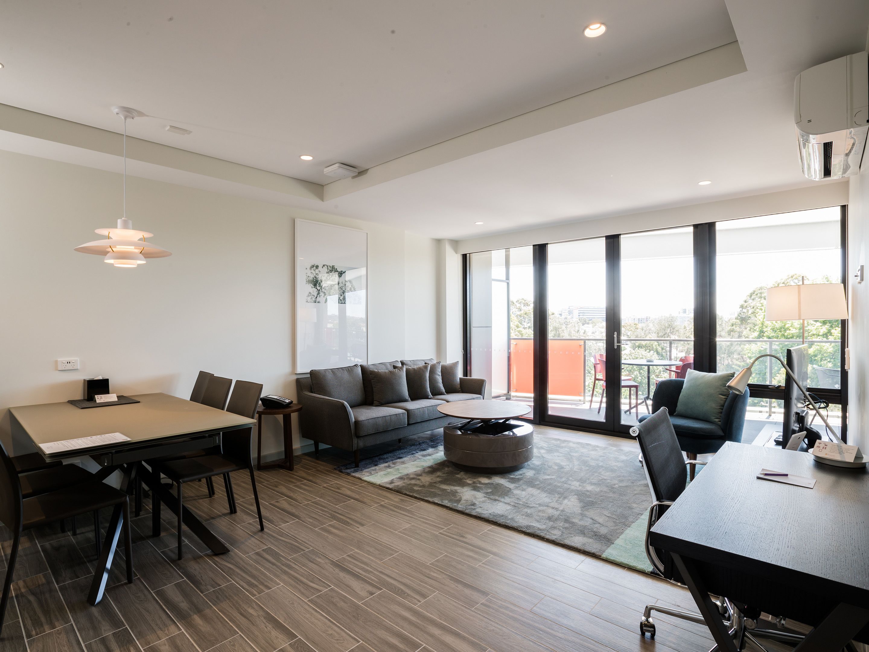 A modern living room with a dining area, large windows, and a view of the outdoors.