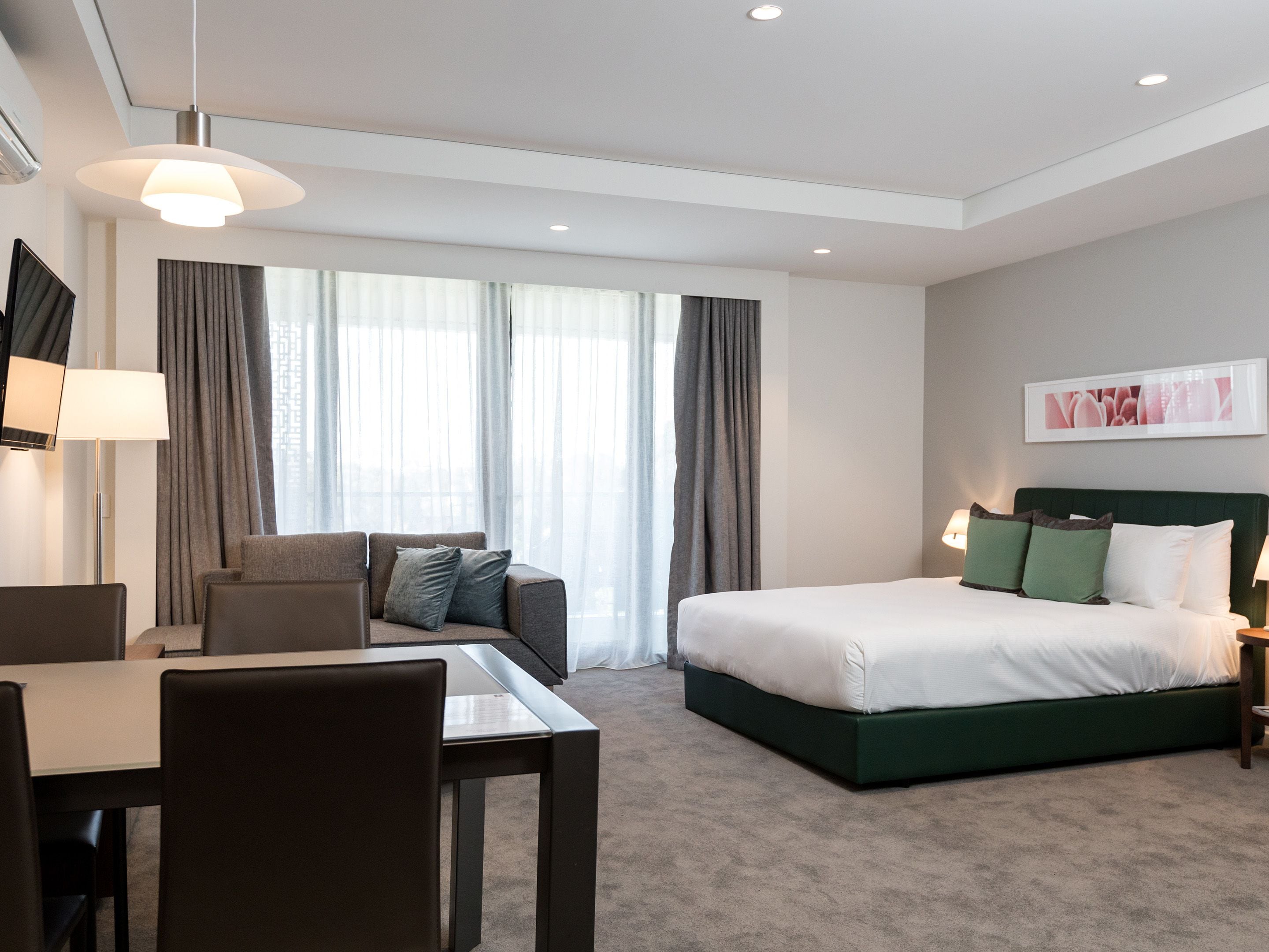 A modern hotel room with a bed, a sofa, a desk, and a chair.