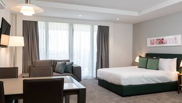 A modern hotel room with a bed, a sofa, a desk, and a chair.