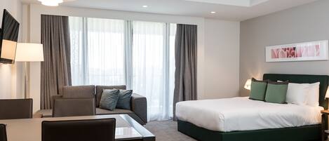 Una habitación de hotel moderna con cama, sofá, escritorio y silla.