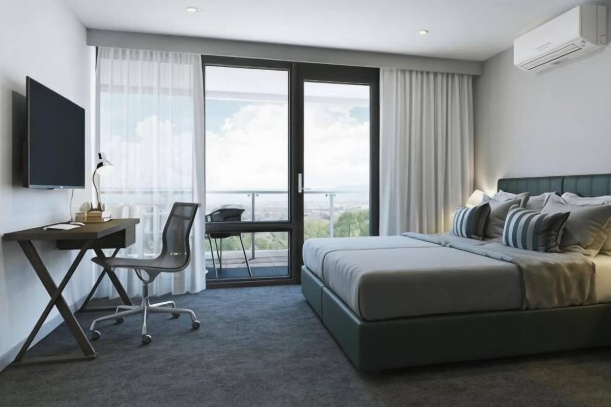 A hotel room with a bed, desk, chair, and a TV.