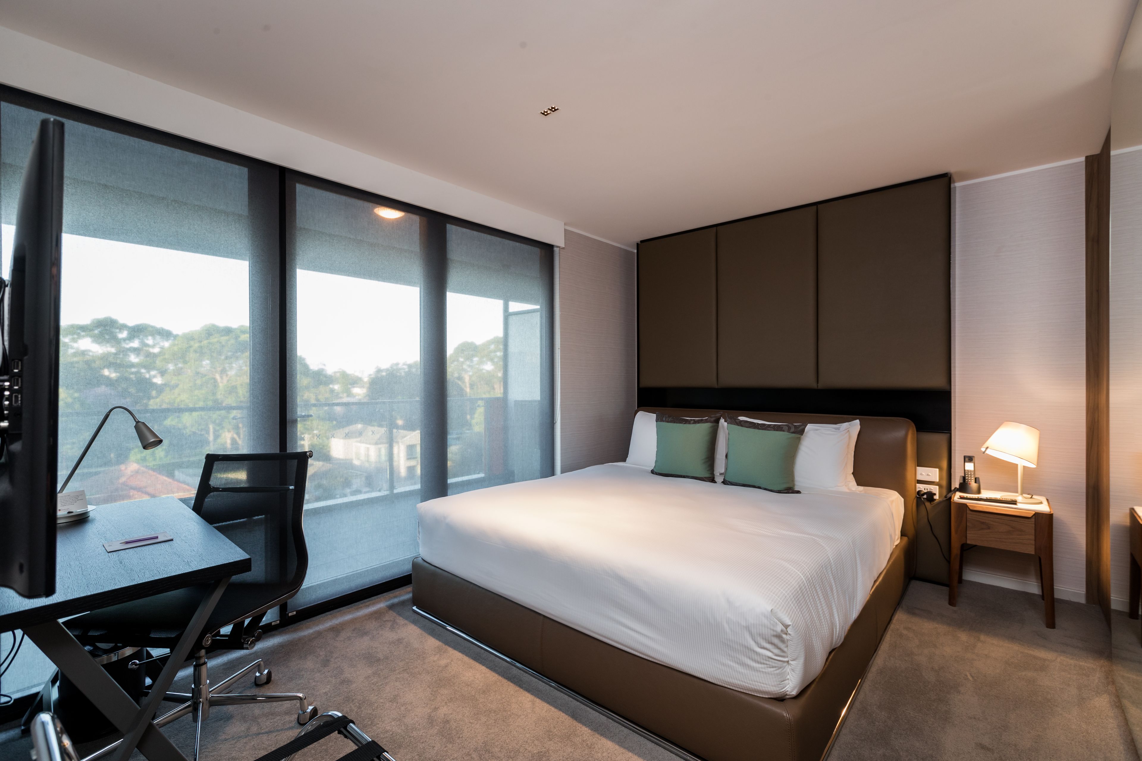Ein modernes Hotelzimmer mit einem großen Bett, einem Schreibtisch und einem Sessel.