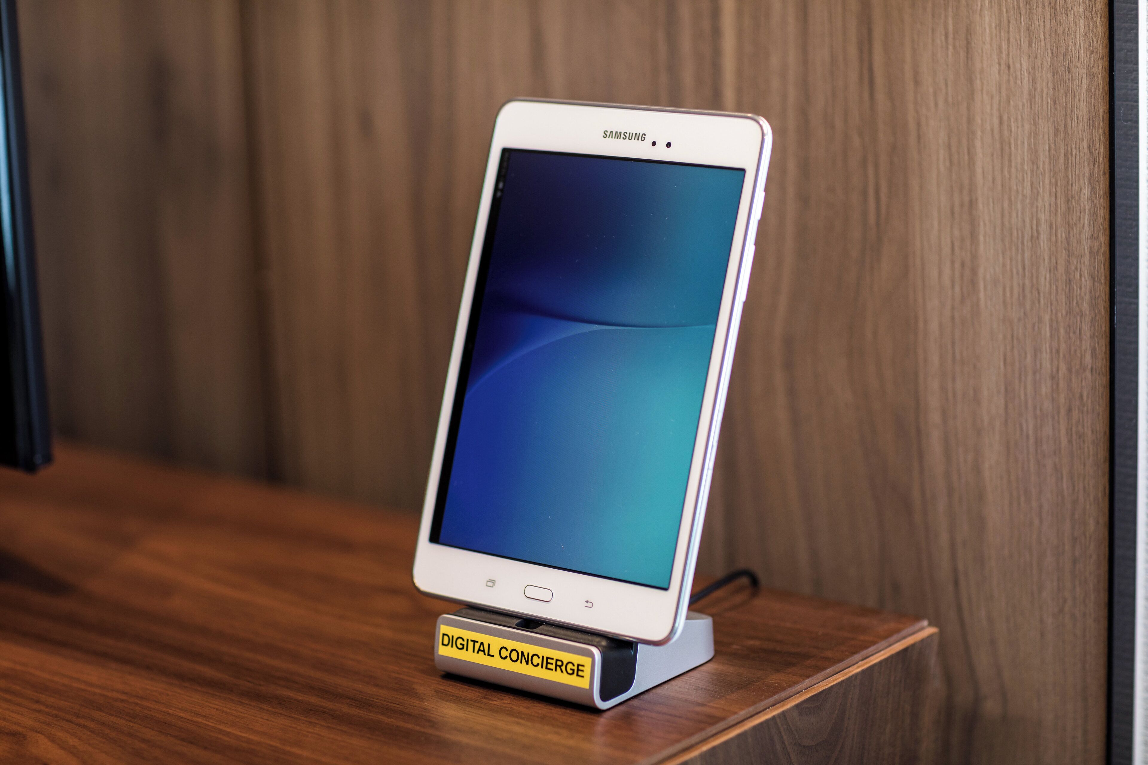 A white Samsung smartphone on a digital concierge stand.