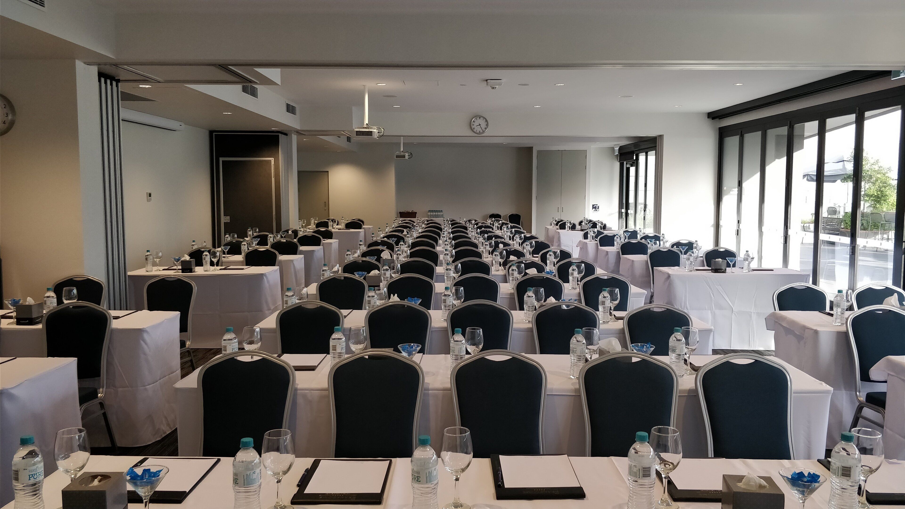 A conference room with rows of tables, chairs, and water bottles.