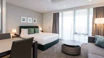 Una habitación de hotel moderna con una cama bien hecha, una zona de comedor y un sofá.