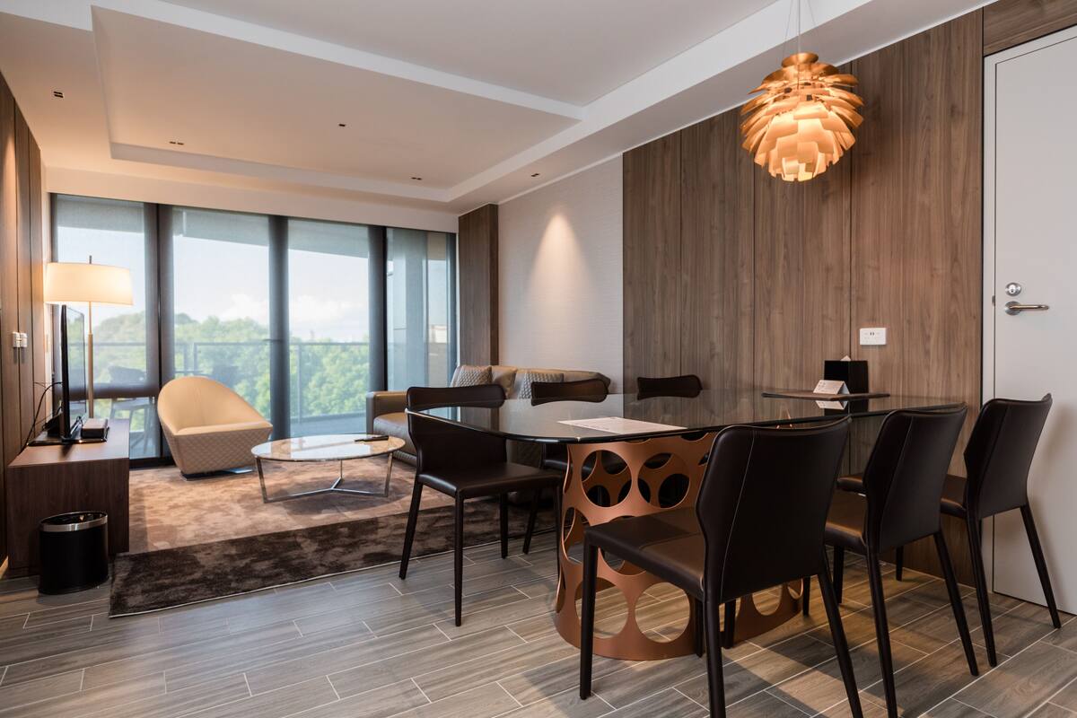 A modern dining area with a round table, black chairs, and a unique wooden side table.