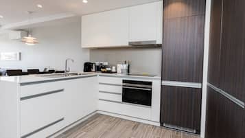A modern kitchen with white cabinetry, a built-in oven, and a dark wood accent wall.