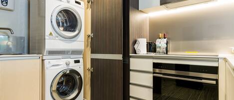 A compact kitchen with a front-loading washer, a built-in oven, and a microwave.