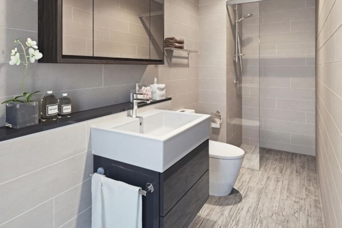 Un baño moderno con un lavabo blanco, muebles oscuros, inodoro y zona de ducha.