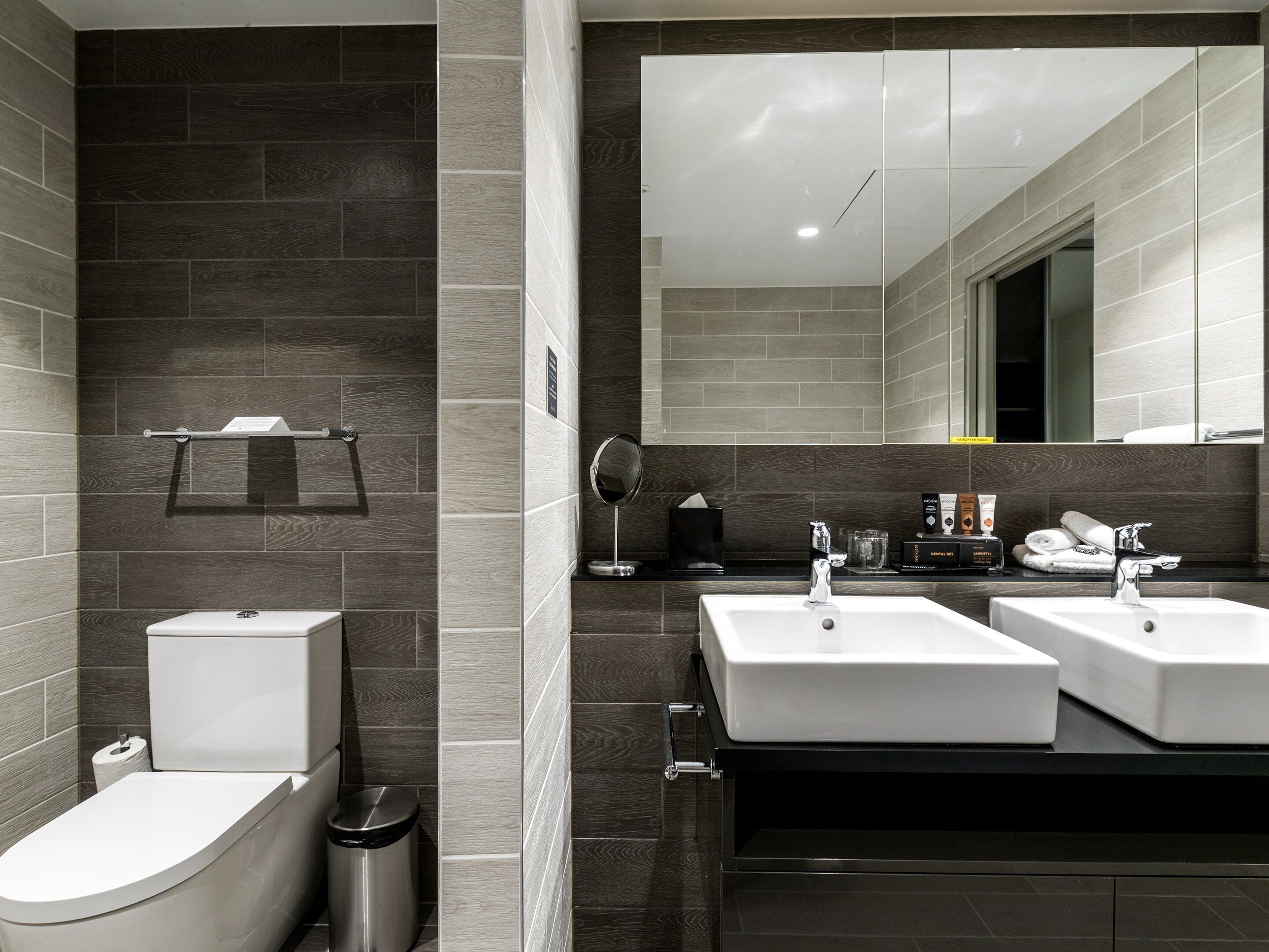 A modern bathroom with a toilet, bidet, and two sinks.