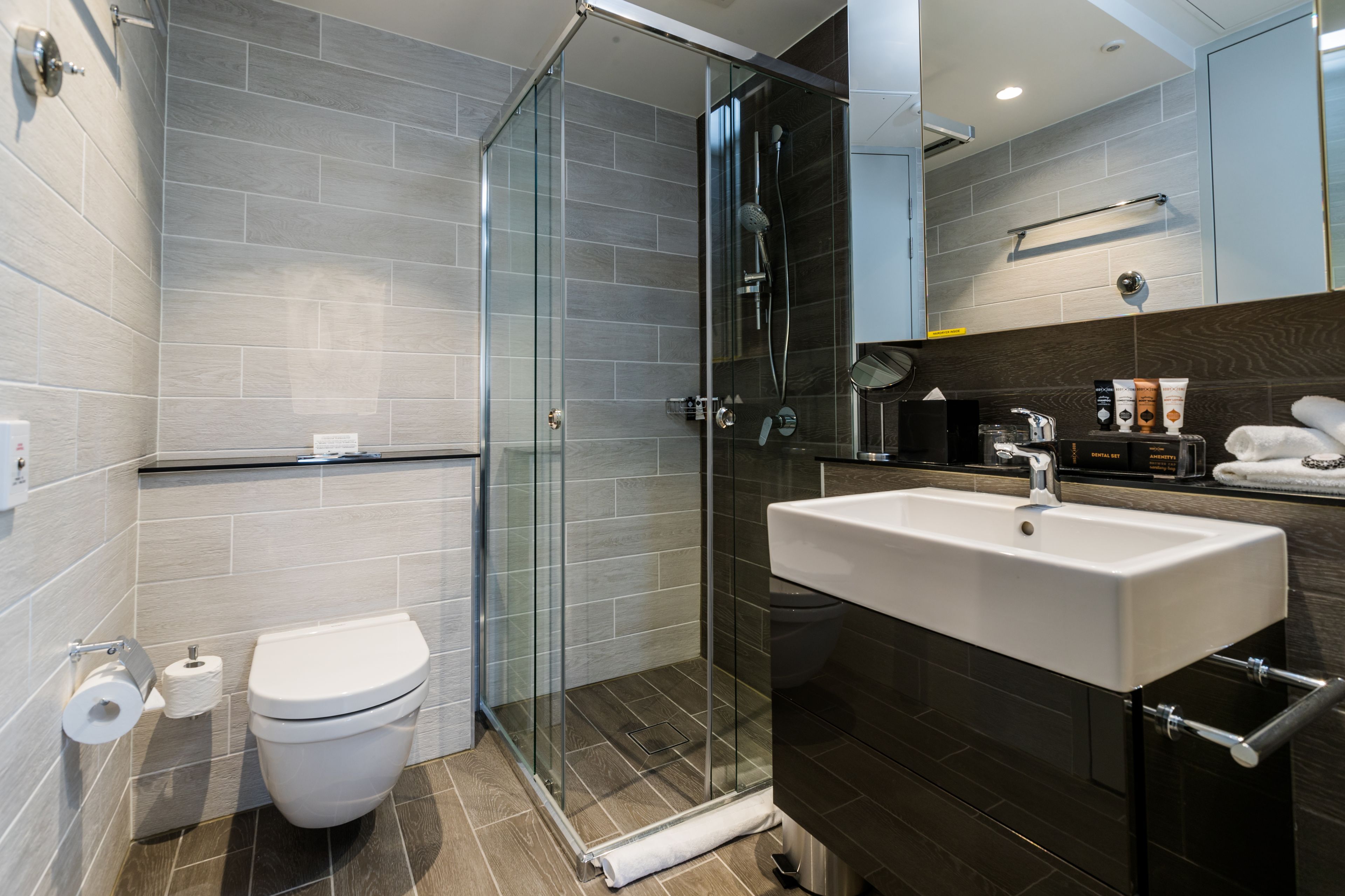 A modern bathroom with a glass-enclosed shower, a white sink, and a toilet.