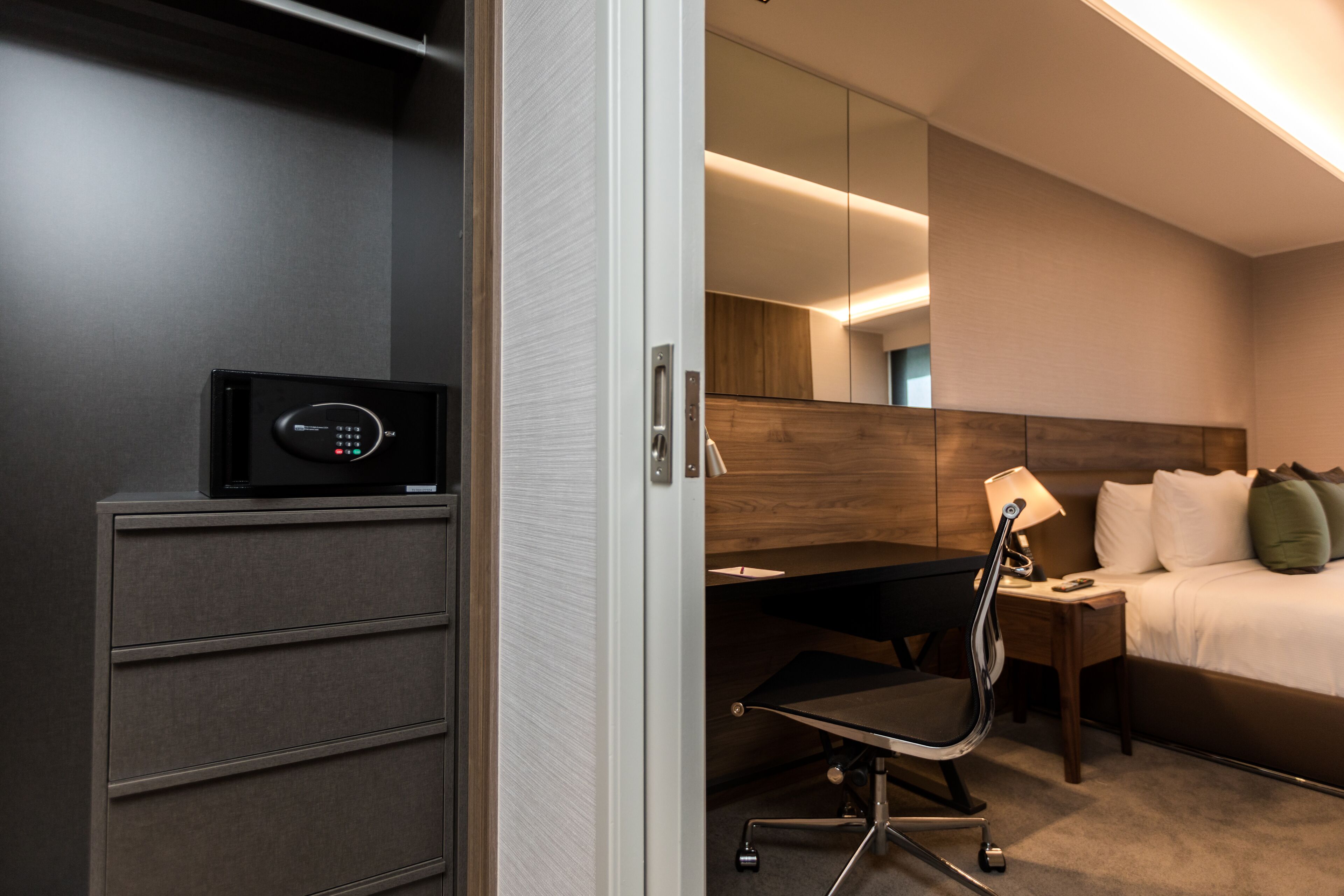 A hotel room with a desk, chair, bed, and a minibar.
