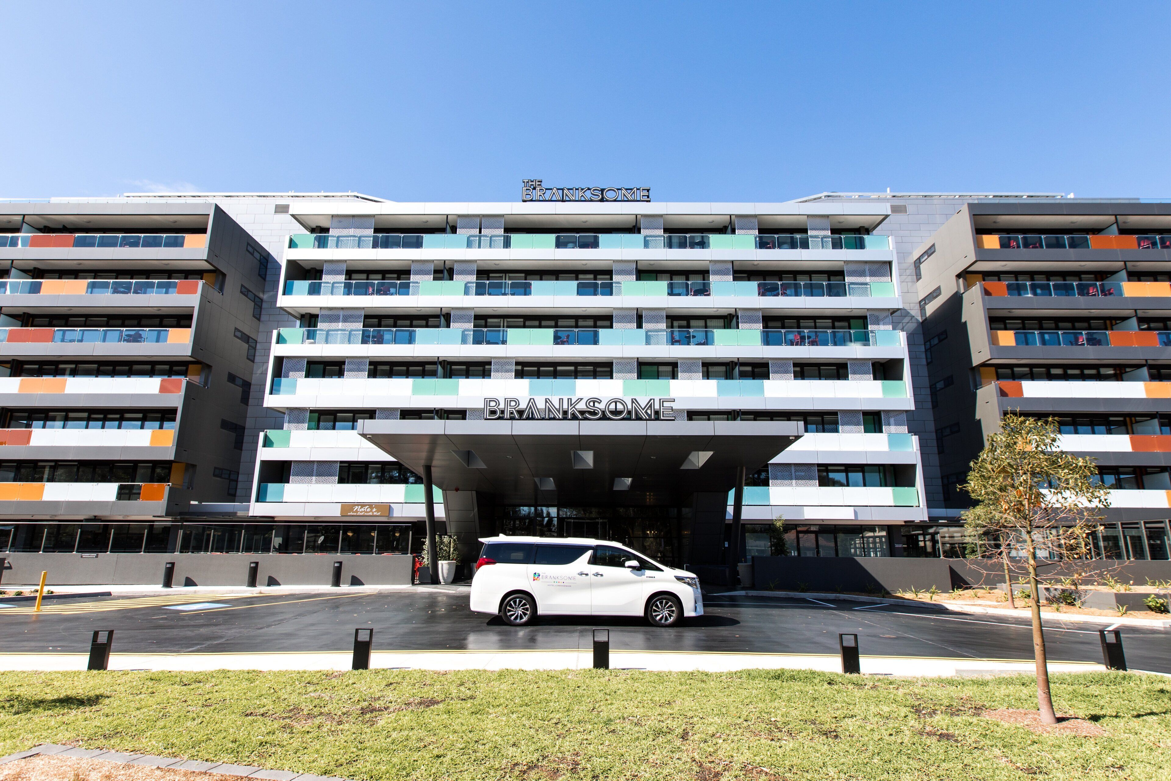 A multi-story hotel with a modern design, featuring balconies and a prominent entrance.