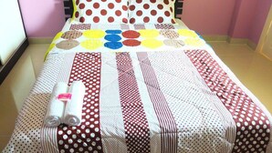 Una cama con un colcha colorida y dos toallas enrolladas.