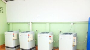 Cuatro dispensadores de agua frente a una pared verde con una pizarra encima.